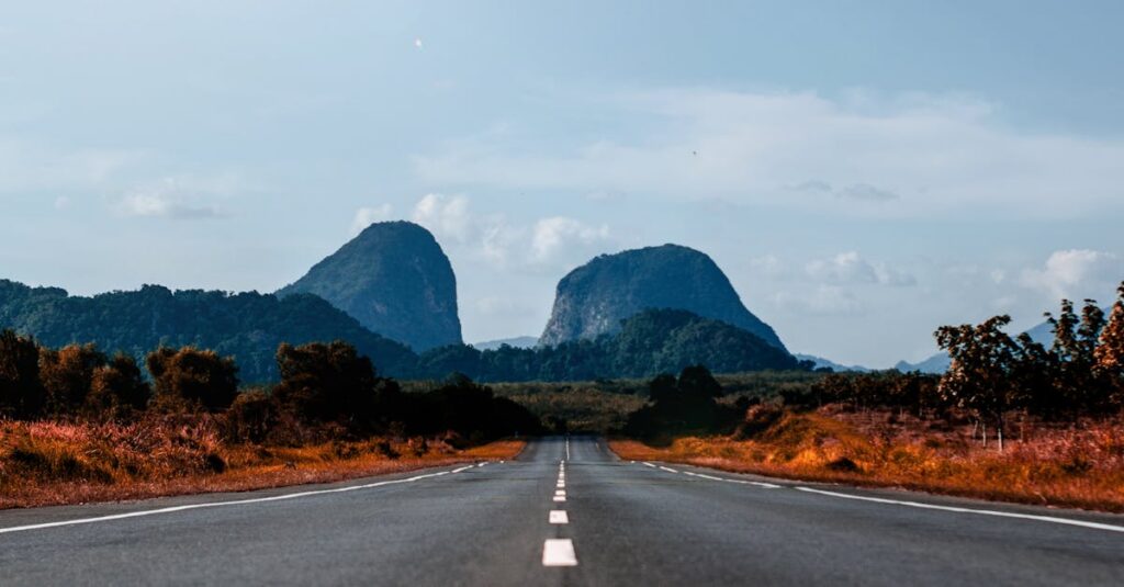 Long straight road leading to distant mountains under a bright blue sky.