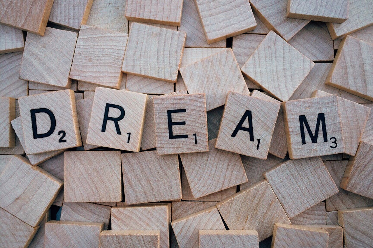 Close-up of wooden Scrabble tiles spelling the word 'DREAM', symbolizing creativity and imagination.